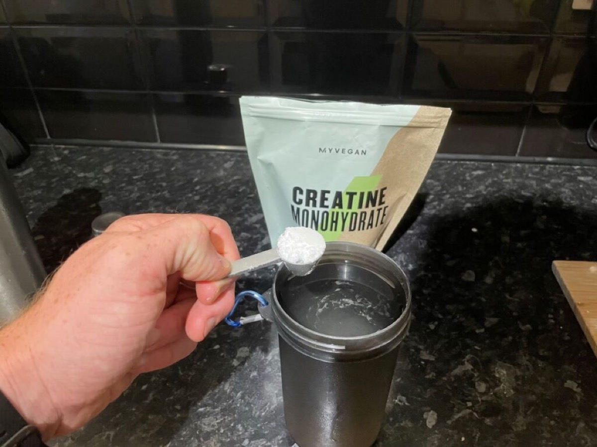 Cucharada de polvo blanco al lado de un vaso de agua