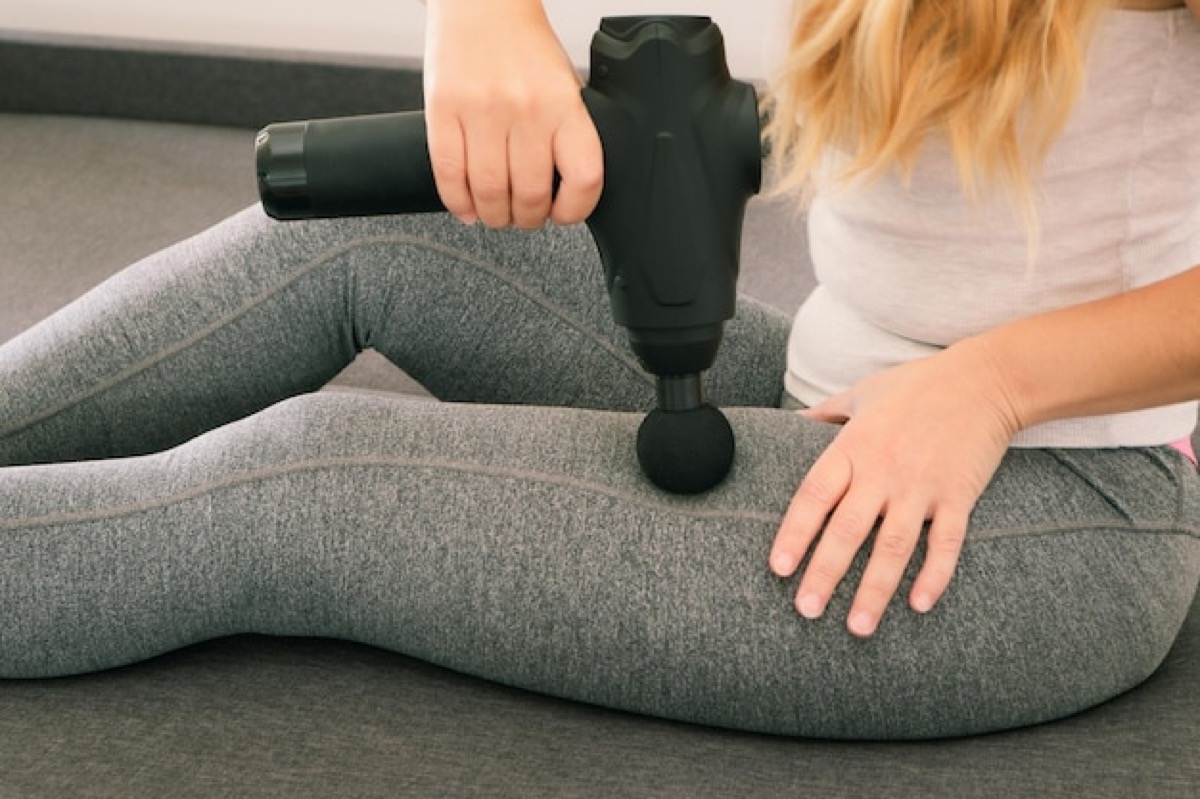 Pistola de masaje en un muslo