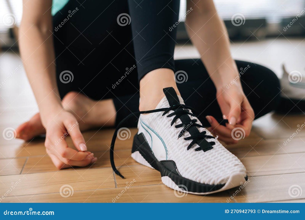 Persona atándose los zapatos de entrenamiento de mala gana
